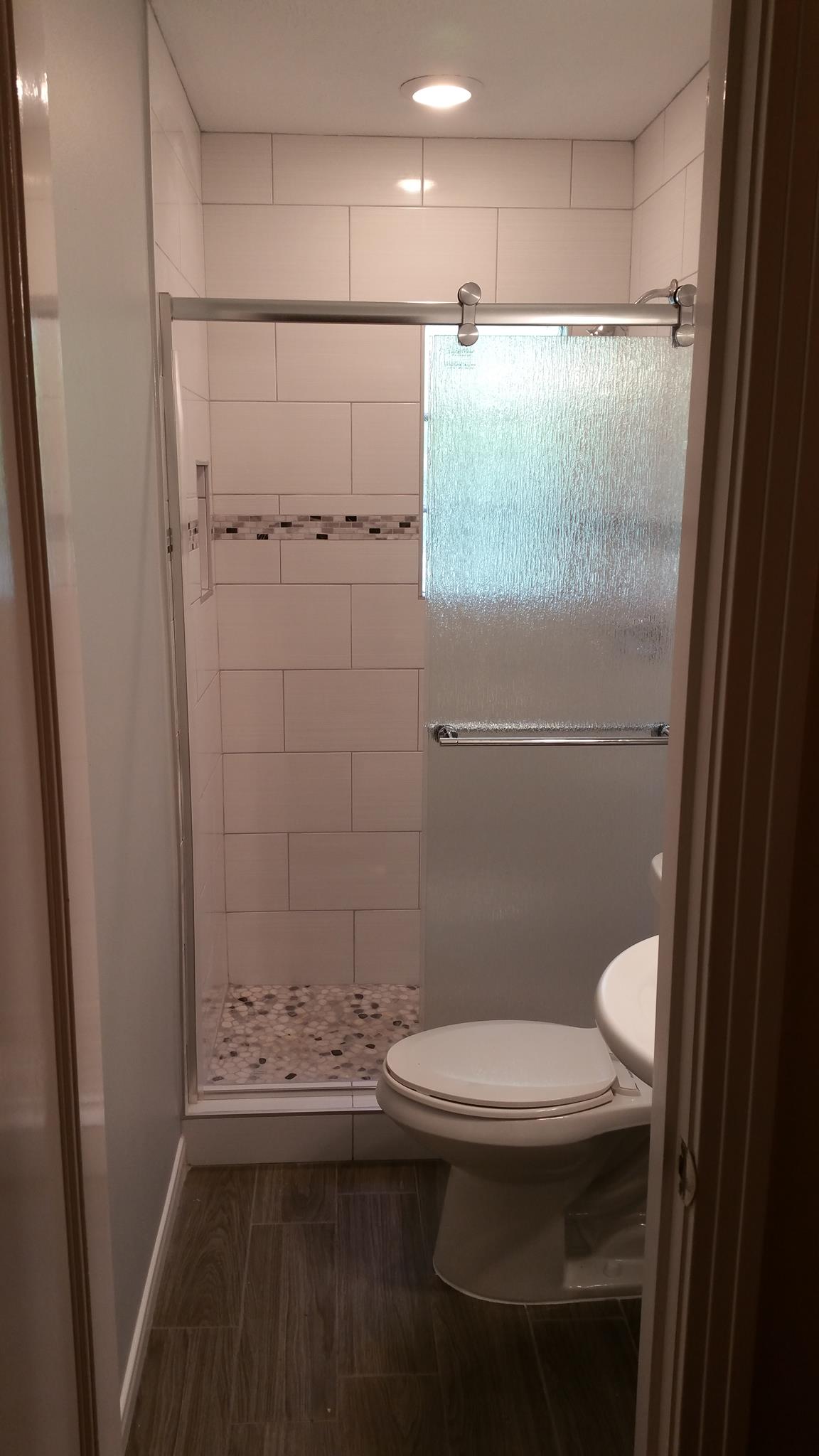 A bathroom with a toilet , sink and shower.