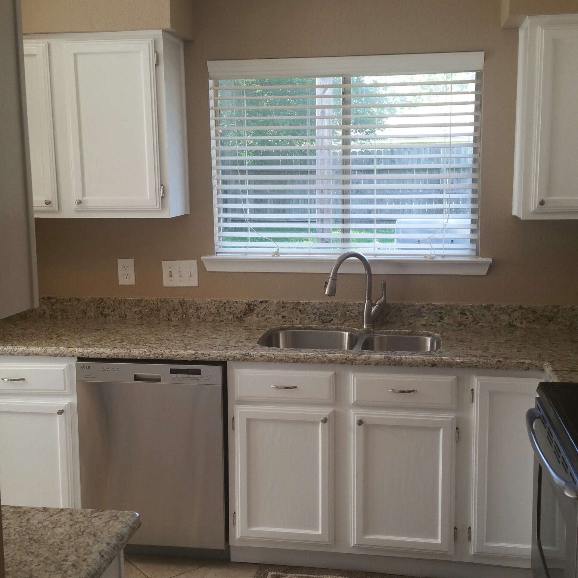 A kitchen with a sink and a window with blinds