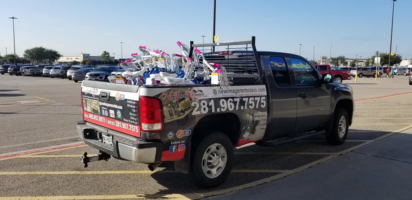 A truck is parked in a parking lot with a lot of toys in the back.