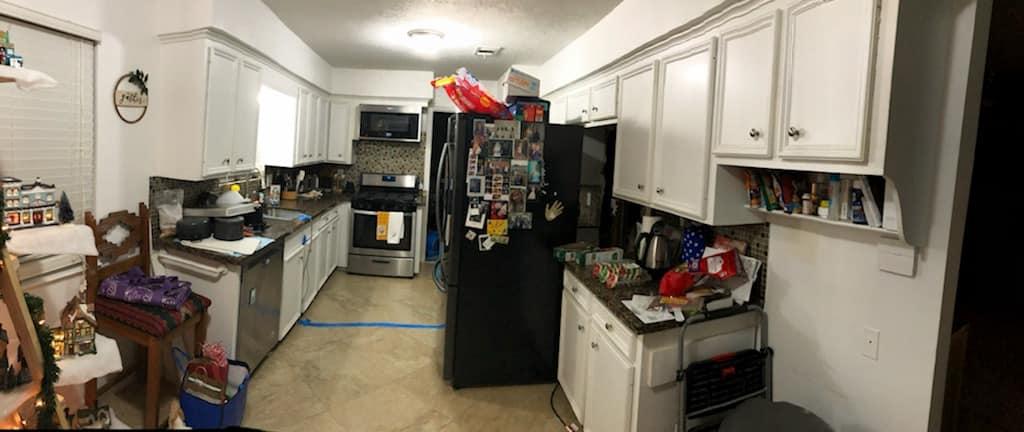 A kitchen with white cabinets , stainless steel appliances , and a black refrigerator.