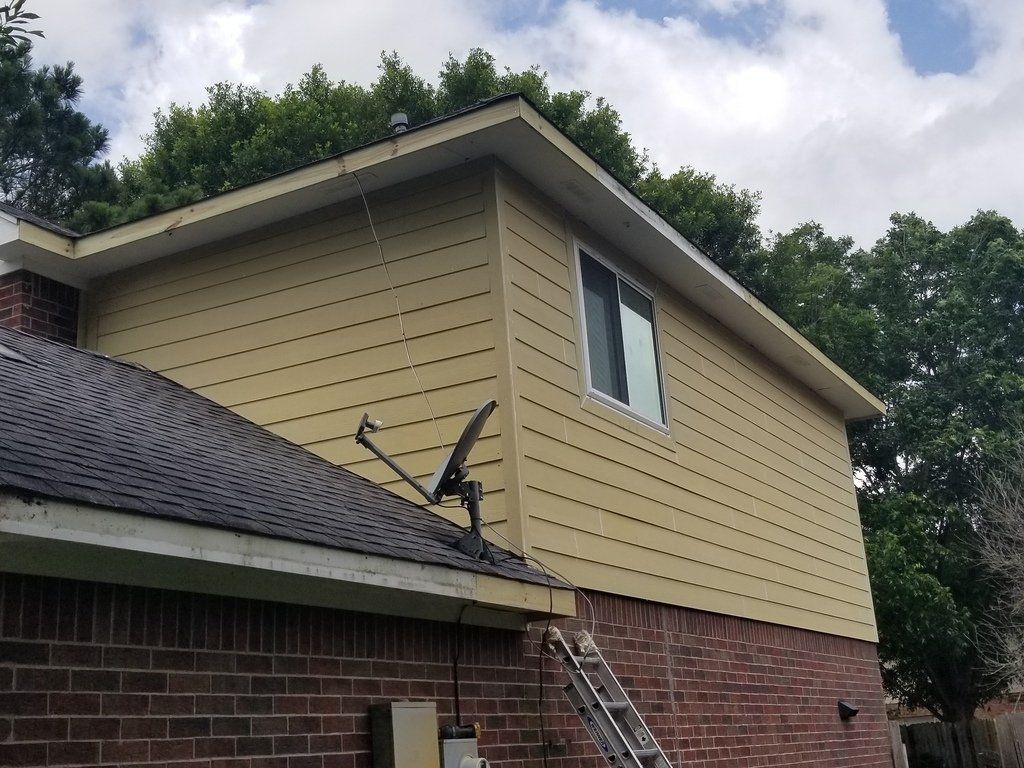 A house with a satellite dish on the roof and a ladder on the side.