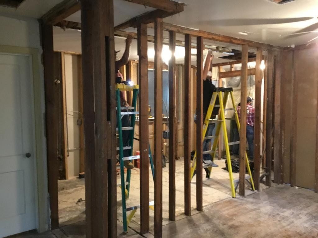 A man is standing on a ladder in a room under construction.