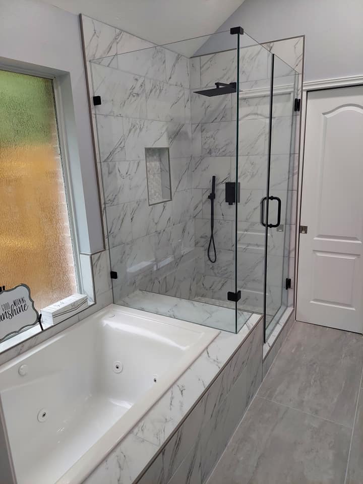 A bathroom with a tub and a shower with a glass door.