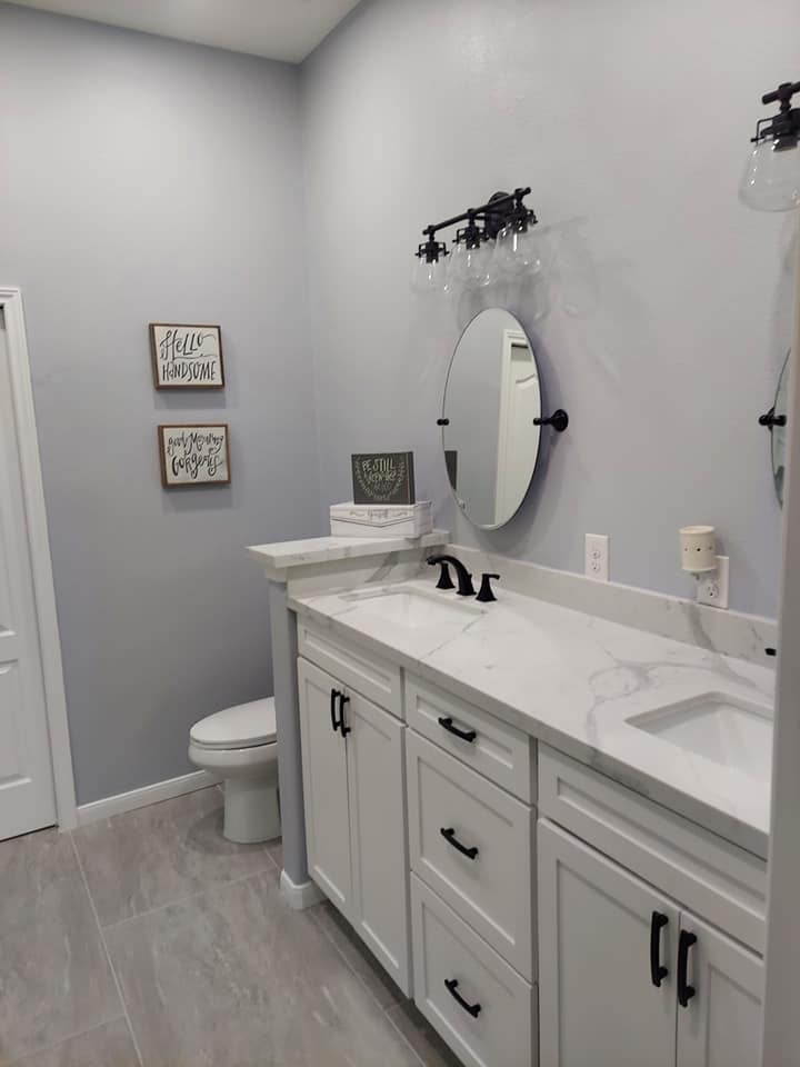 A bathroom with two sinks , a toilet , and a mirror.