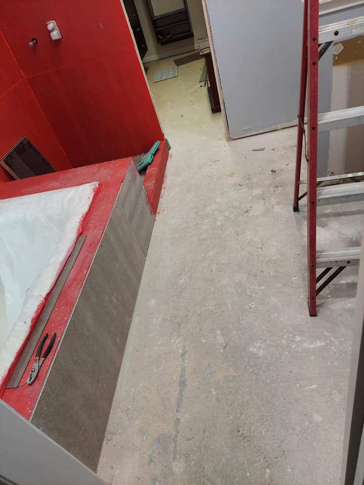 A bathroom with a bathtub and a ladder on the floor