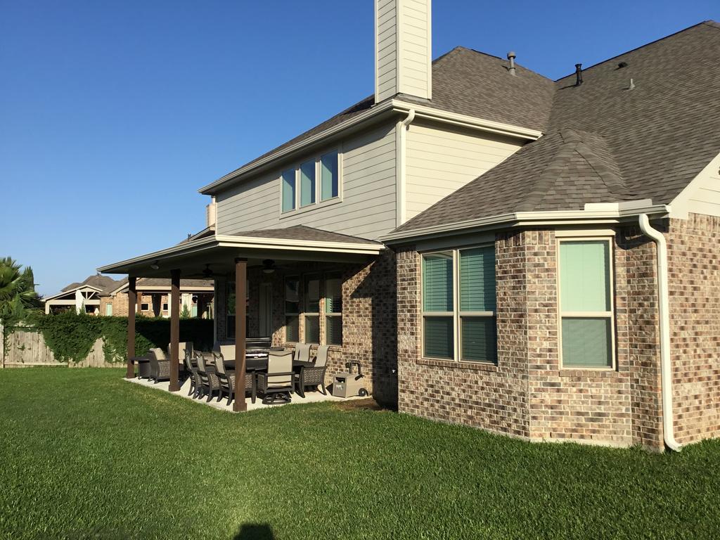 A large brick house with a covered patio in the backyard.