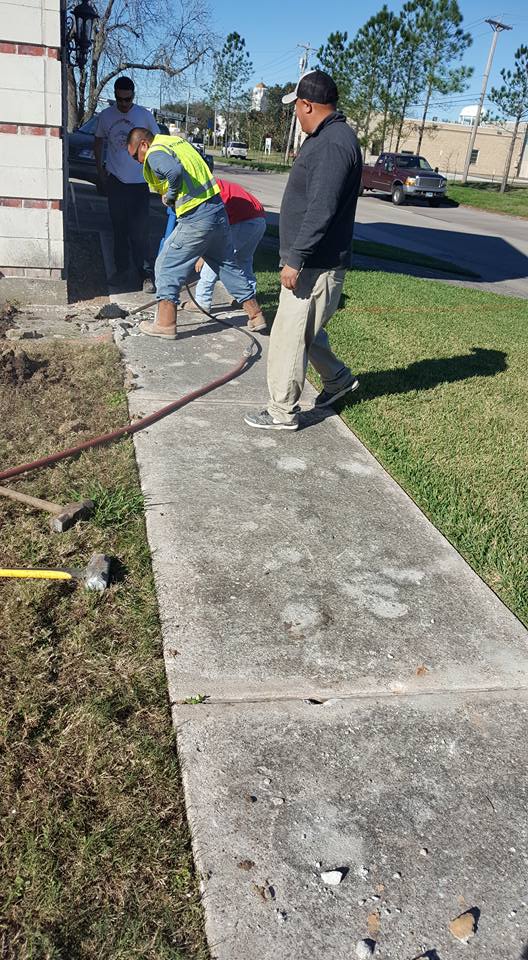 A group of men are working on a sidewalk.