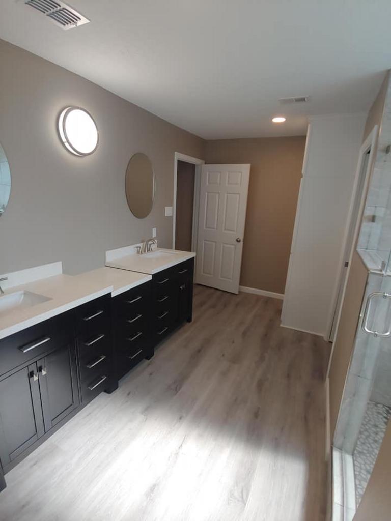 A bathroom with two sinks , a mirror and a walk in shower.