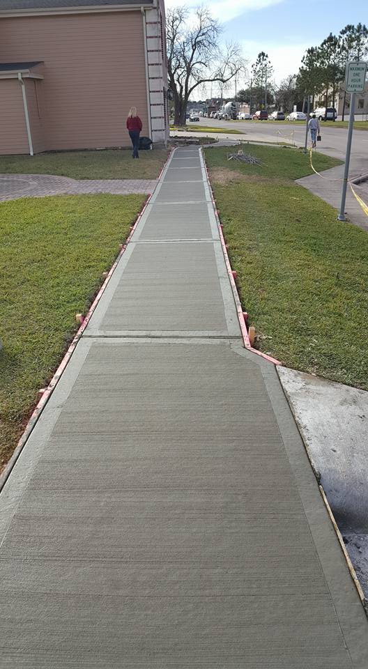 A concrete sidewalk is being built in front of a house.