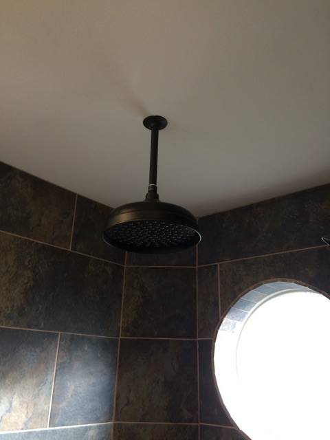 A shower head is hanging from the ceiling in a bathroom