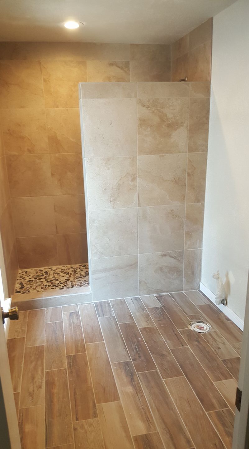 A bathroom with a walk in shower and wooden floors.