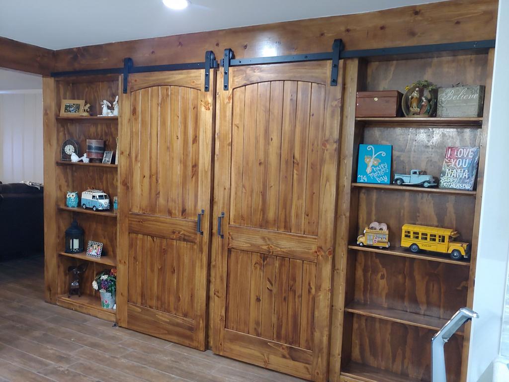 A room with sliding barn doors and shelves filled with toys.