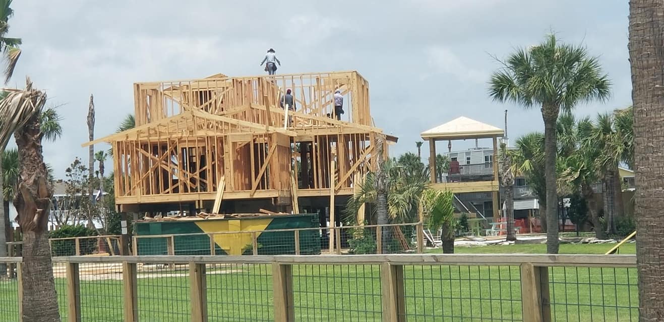 A house that is being built with a fence in the foreground