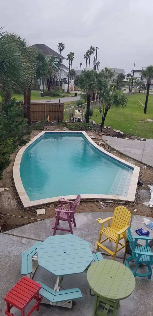 A large swimming pool with a picnic table and chairs around it.