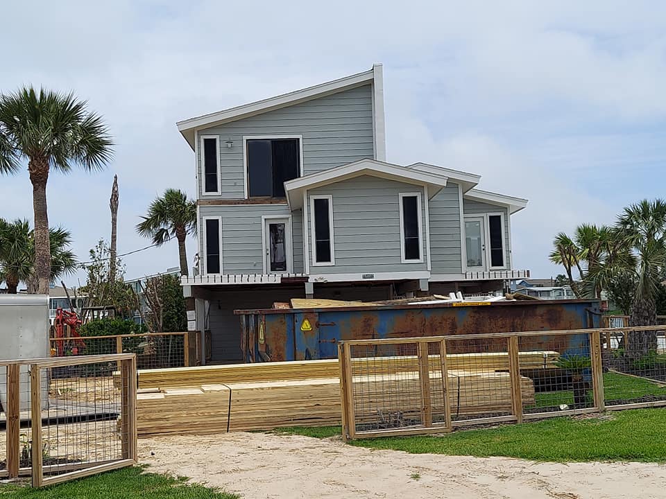 A house is being built on stilts on the beach.