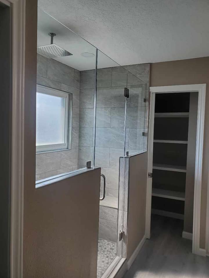 A bathroom with a walk in shower and a closet.