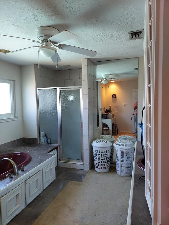 A bathroom with two laundry baskets and a ceiling fan