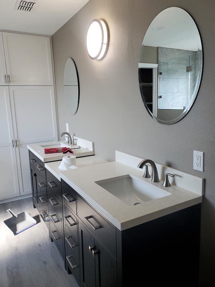 A bathroom with two sinks and two round mirrors