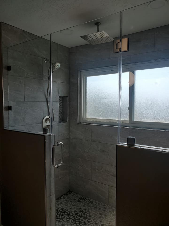 A bathroom with a walk in shower and a window.