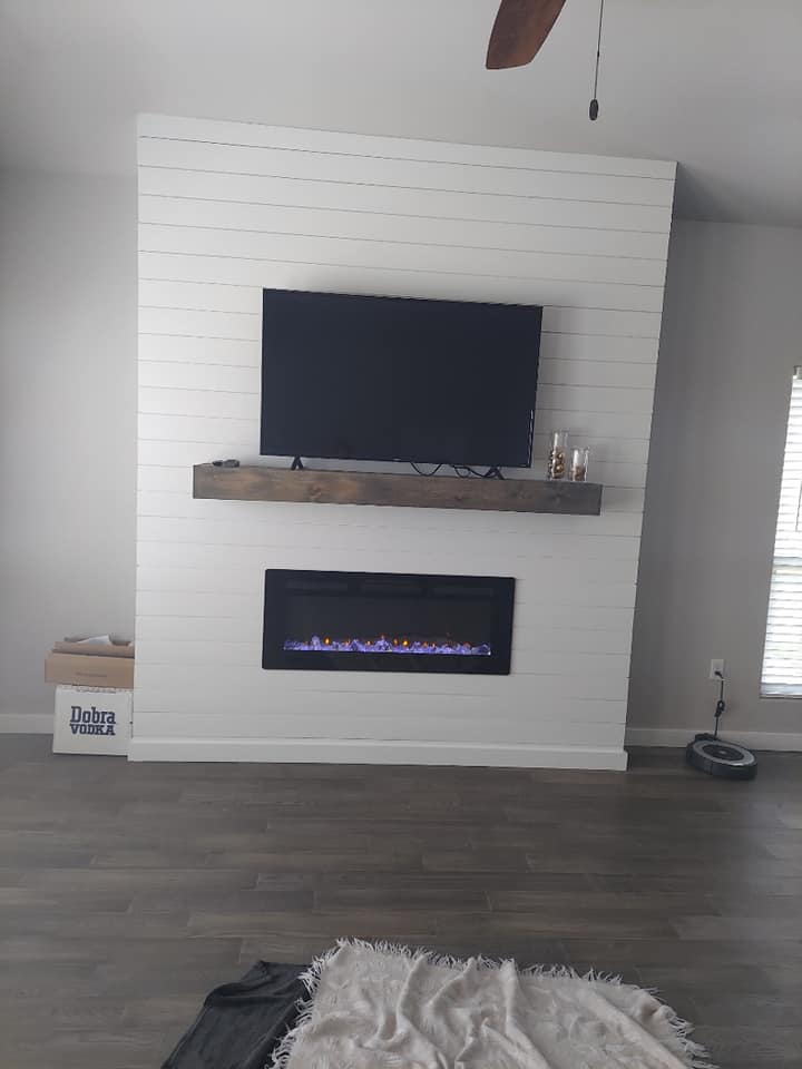 A living room with a fireplace and a flat screen tv on the wall.