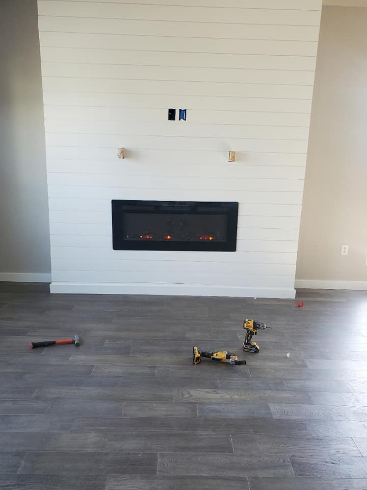 A fireplace is being installed in a living room with a wooden floor.