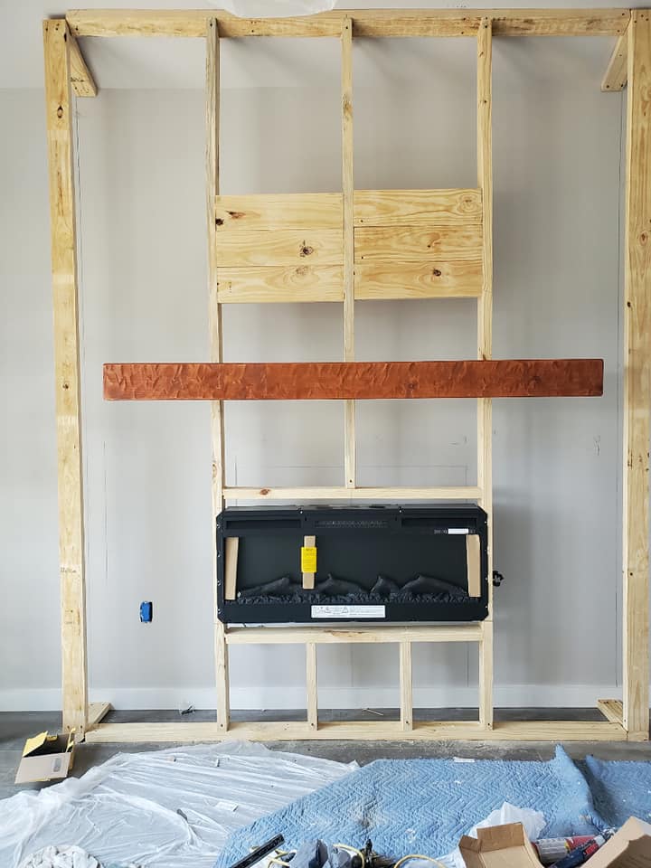 A wooden frame is being built around a fireplace in a living room.