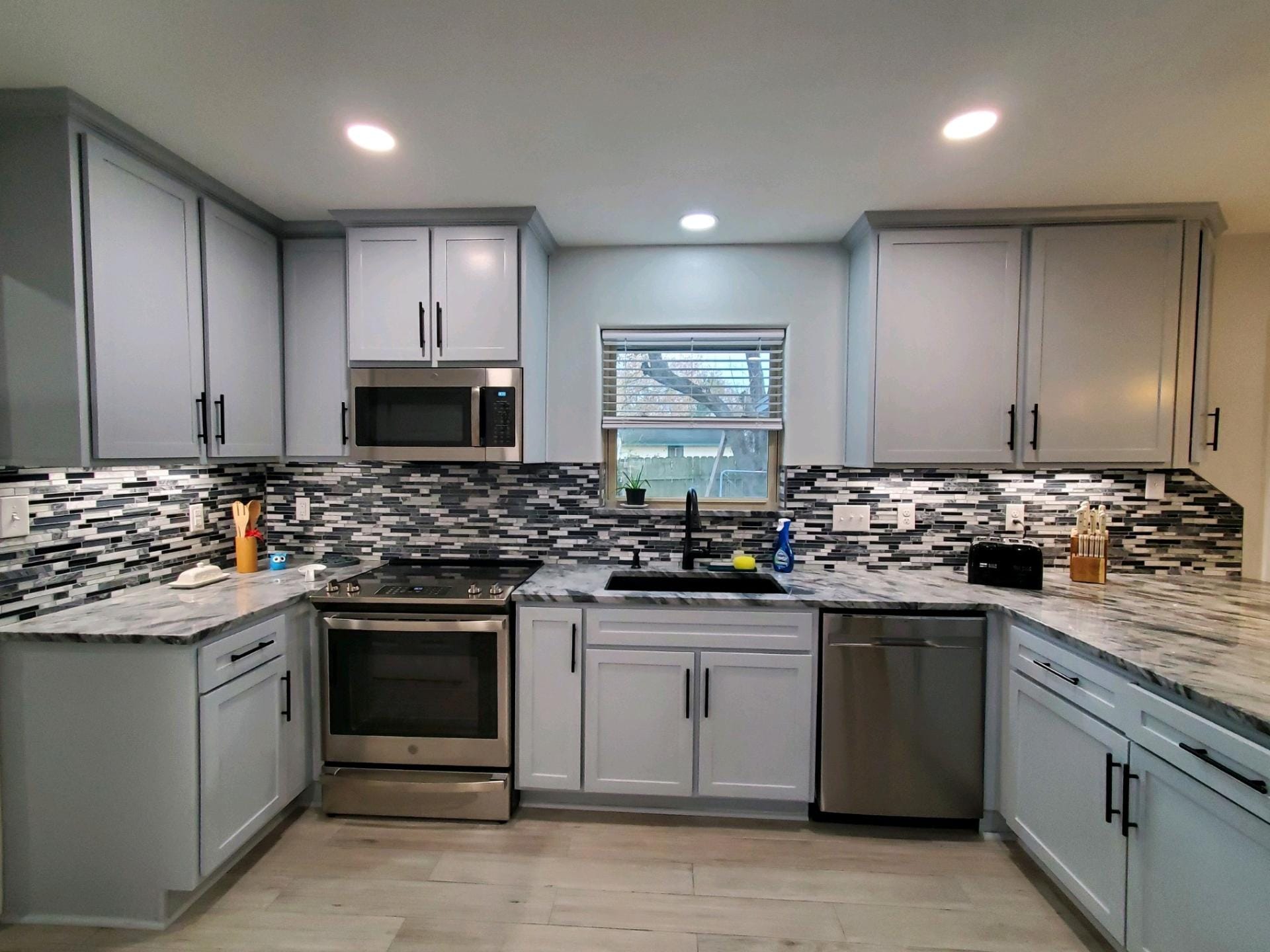 Bright, spacious kitchen with white cabinets, island, and countertops. Three bar stools sit at the island.
