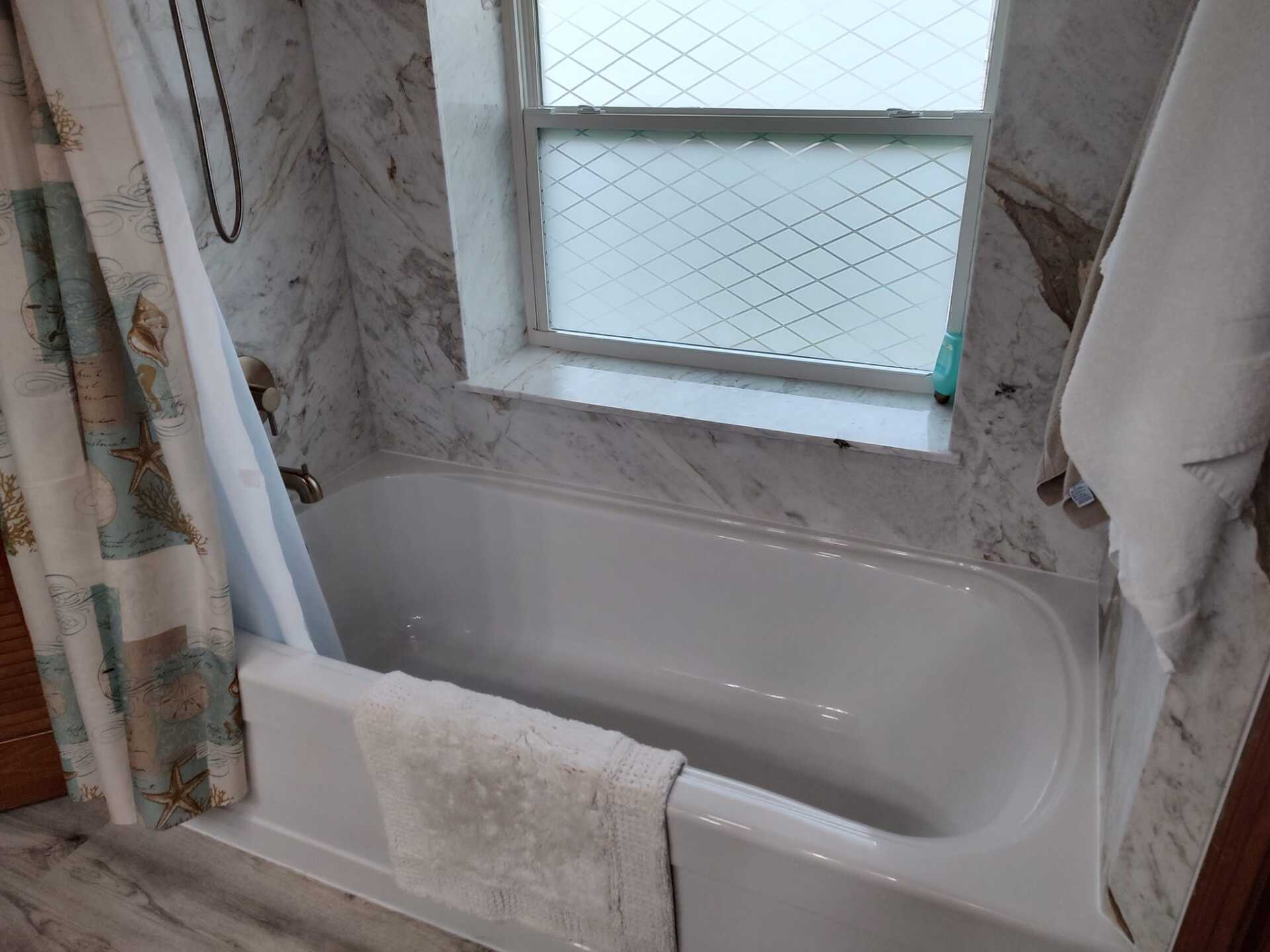 A bathroom with a bathtub and a window.