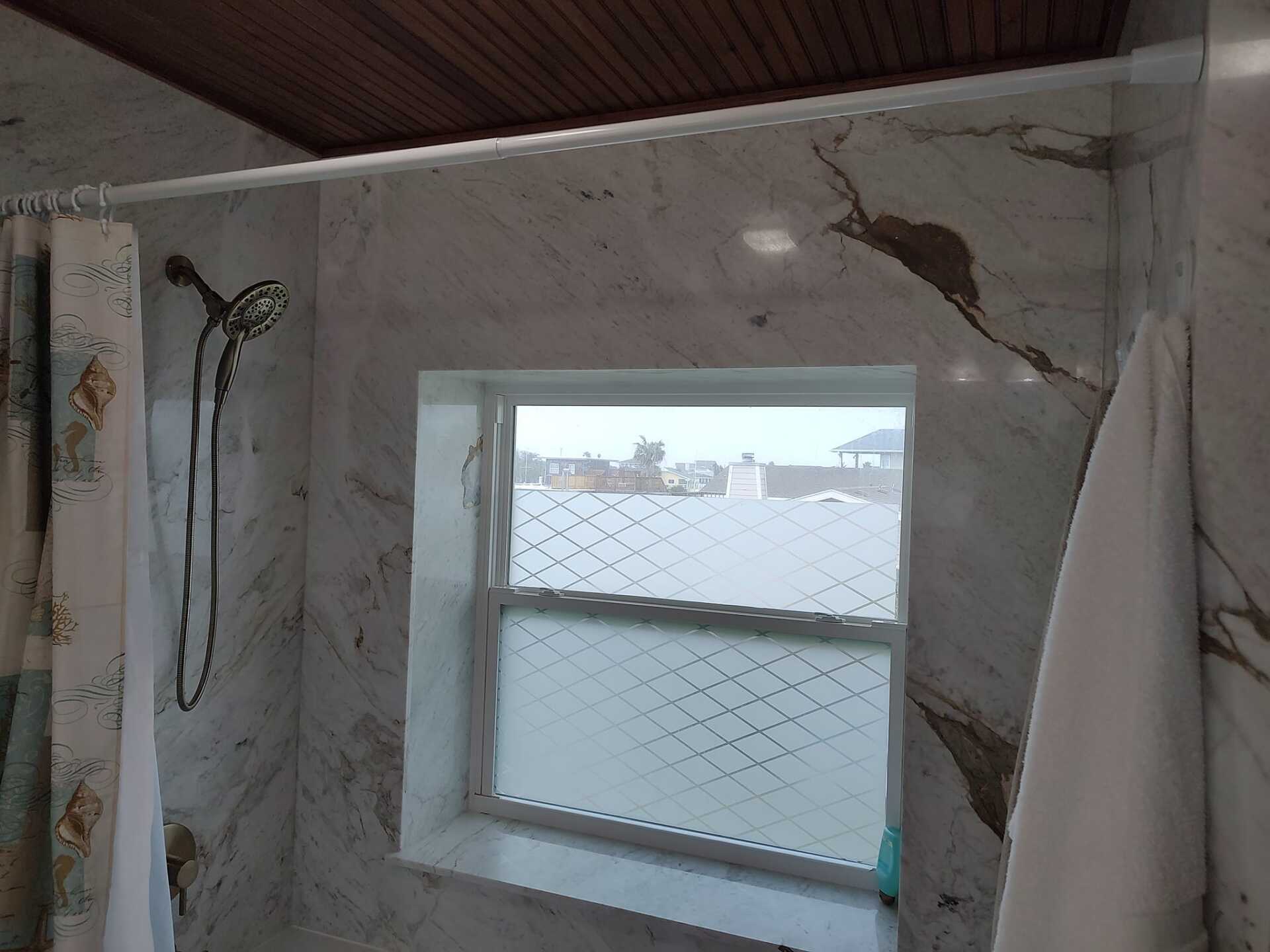 A bathroom with a shower curtain and a window.