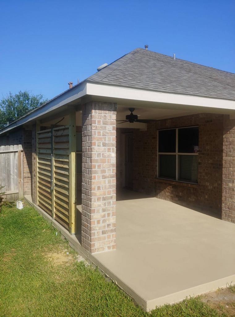 A brick house with a covered patio and a ceiling fan.