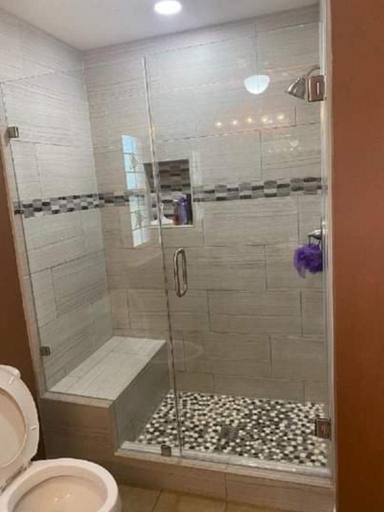 A bathroom with a toilet and a walk in shower with a glass door.