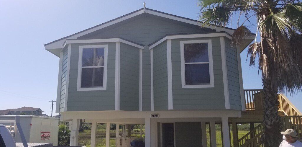 A man is standing in front of a green house.