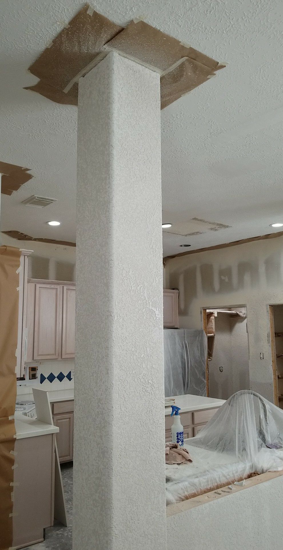 A kitchen with a pillar in the middle of the room.