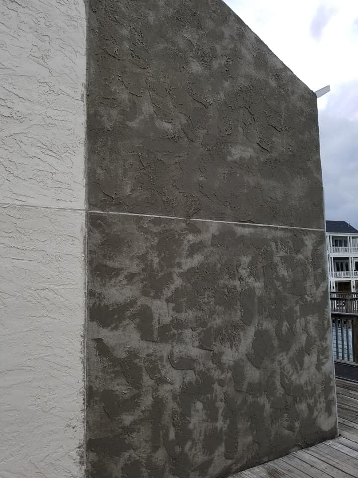 A large concrete wall with a white trim is being painted.