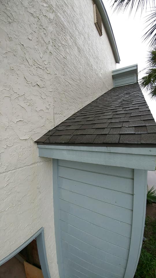 A white house with a blue door and a roof.