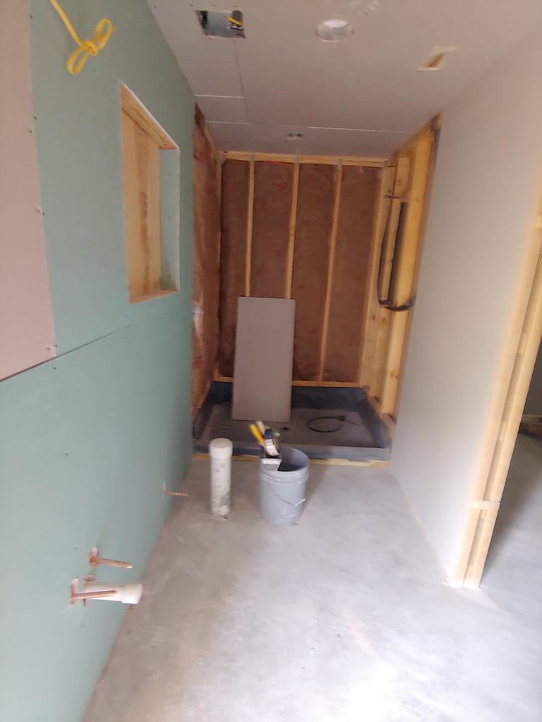 A bathroom under construction with a bucket of paint on the floor.