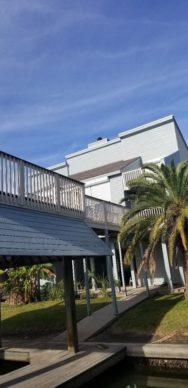 A bridge leading to a house with a palm tree in front of it.