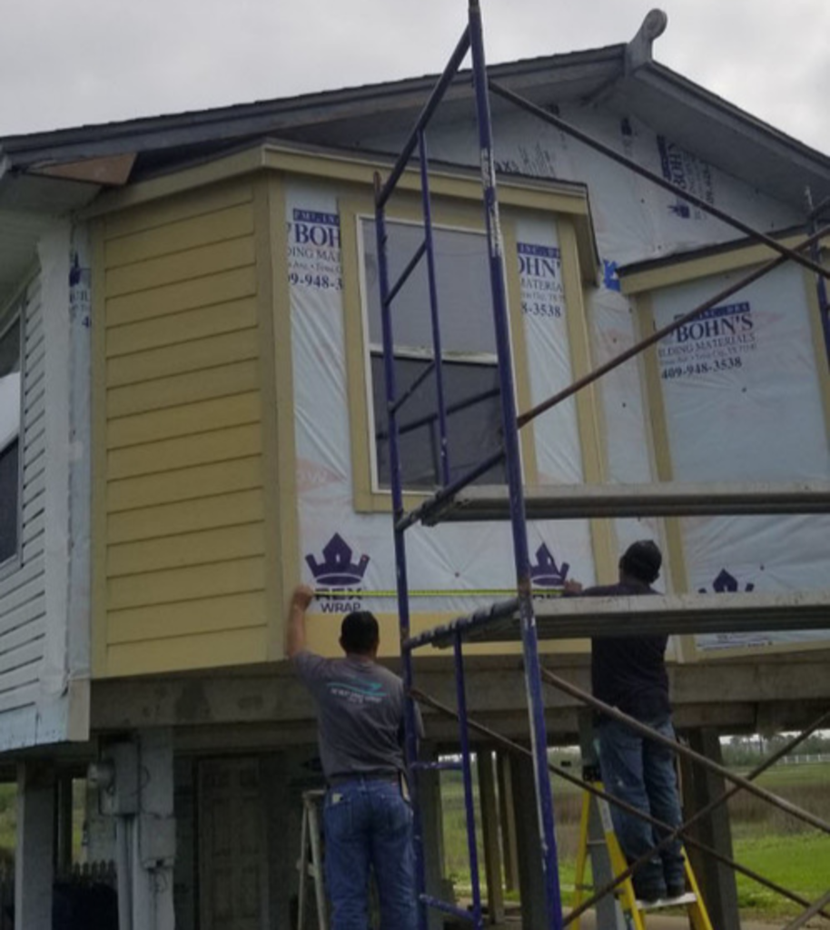 A man is measuring the side of a house with a tape measure