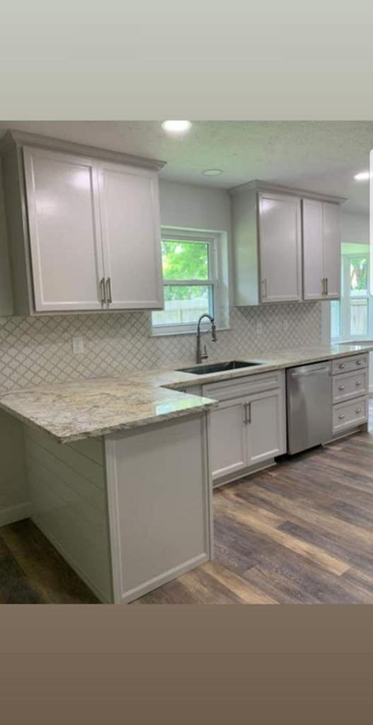 A kitchen with white cabinets , granite counter tops , and stainless steel appliances.