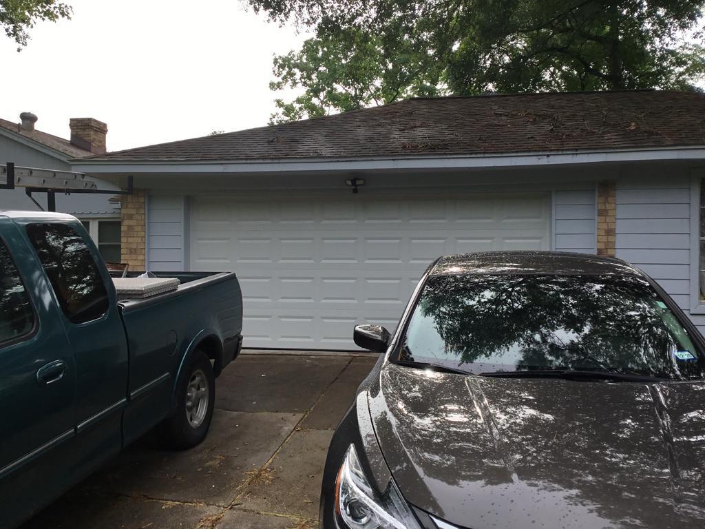 A truck and a car are parked in front of a garage door.
