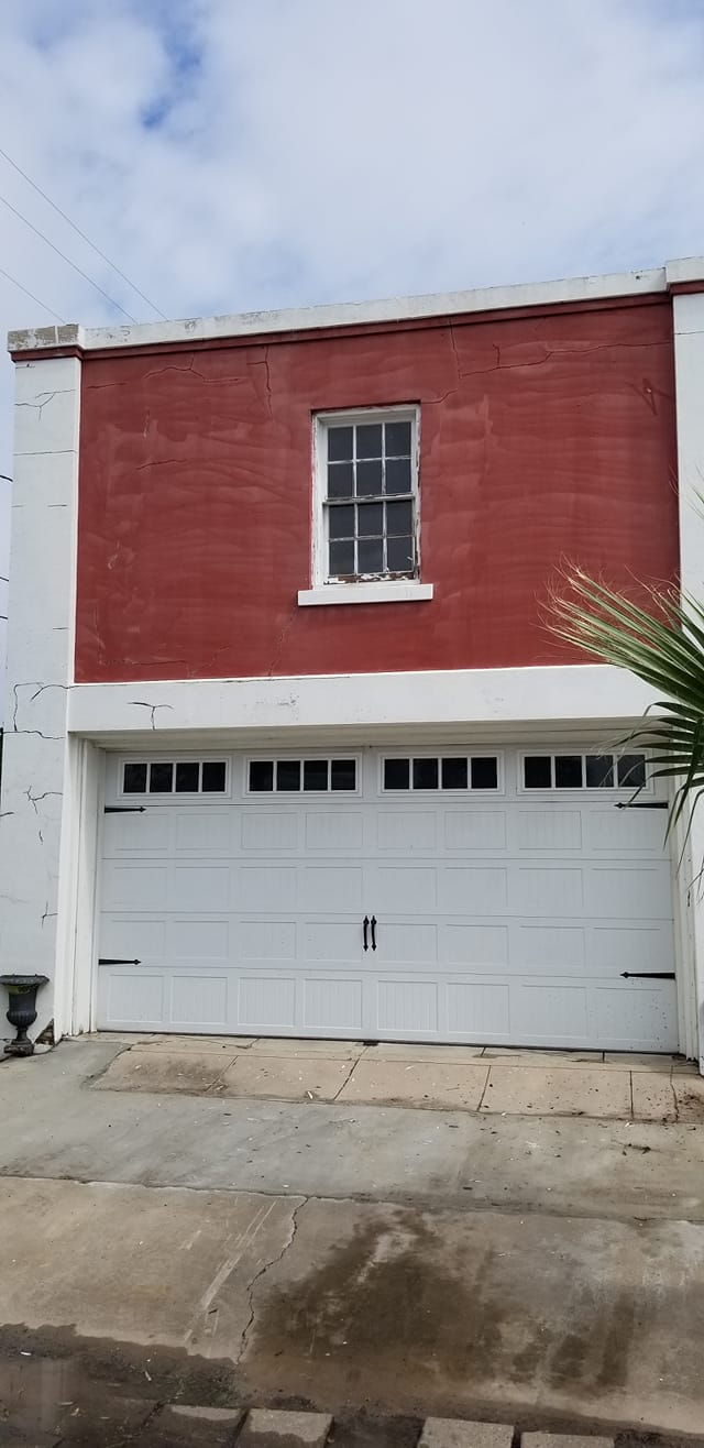 A red and white building with a white garage door and a window.