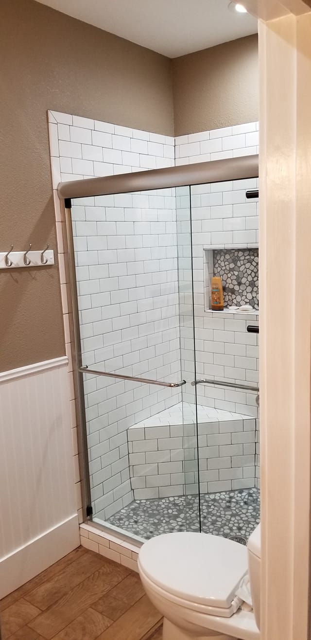 A bathroom with a sliding glass shower door and a toilet.