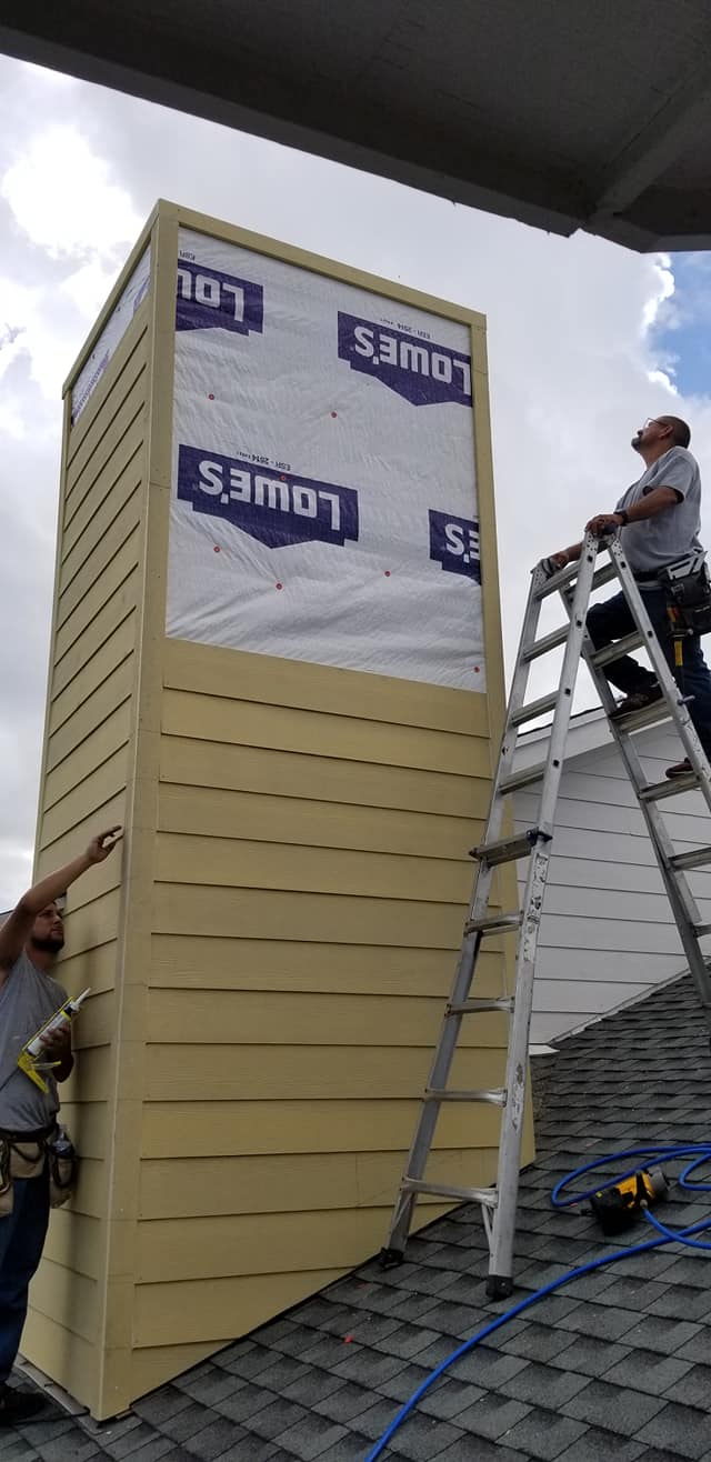 A man is standing on a ladder on top of a roof.