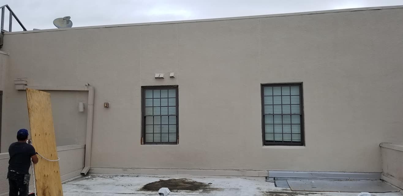 A man is standing in front of a building with two windows.