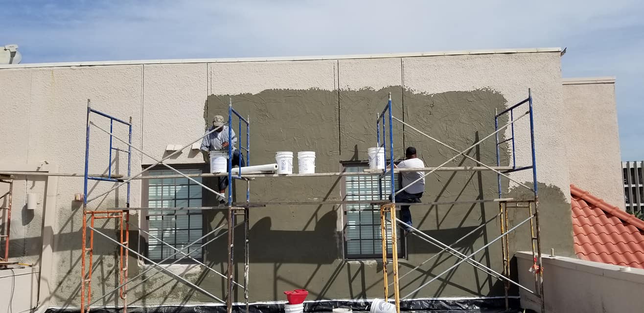 A group of people are painting a building with scaffolding.