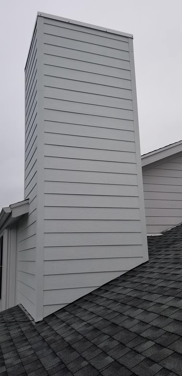 A large white chimney is sitting on top of a roof.