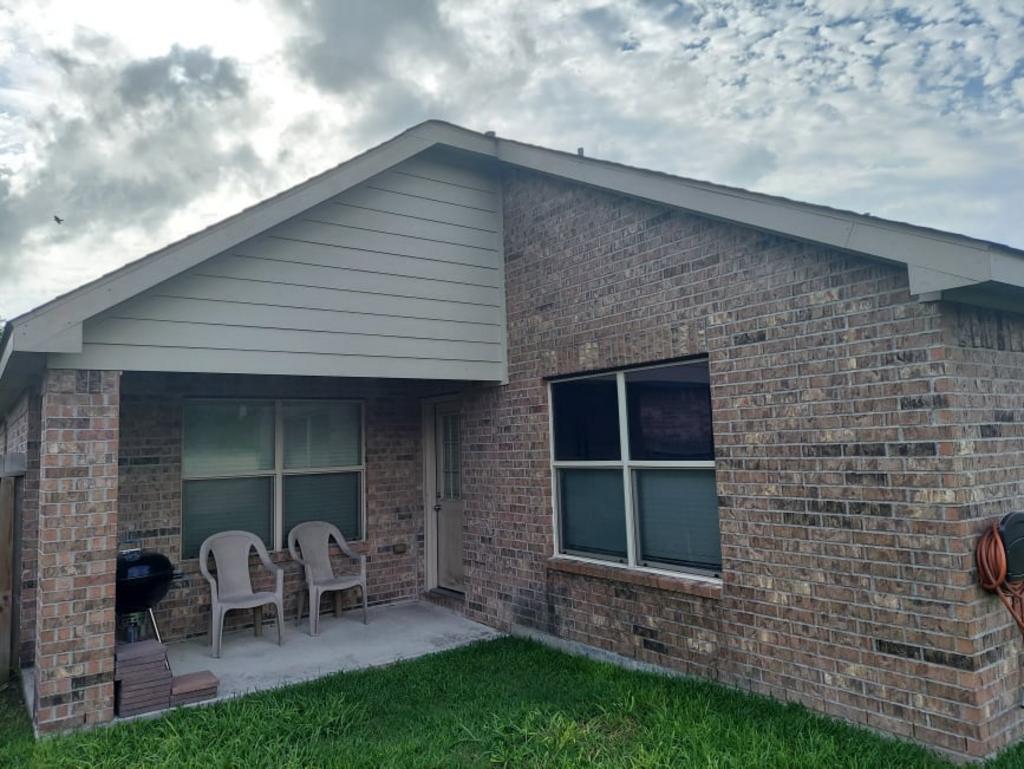 A brick house with a patio and chairs in front of it