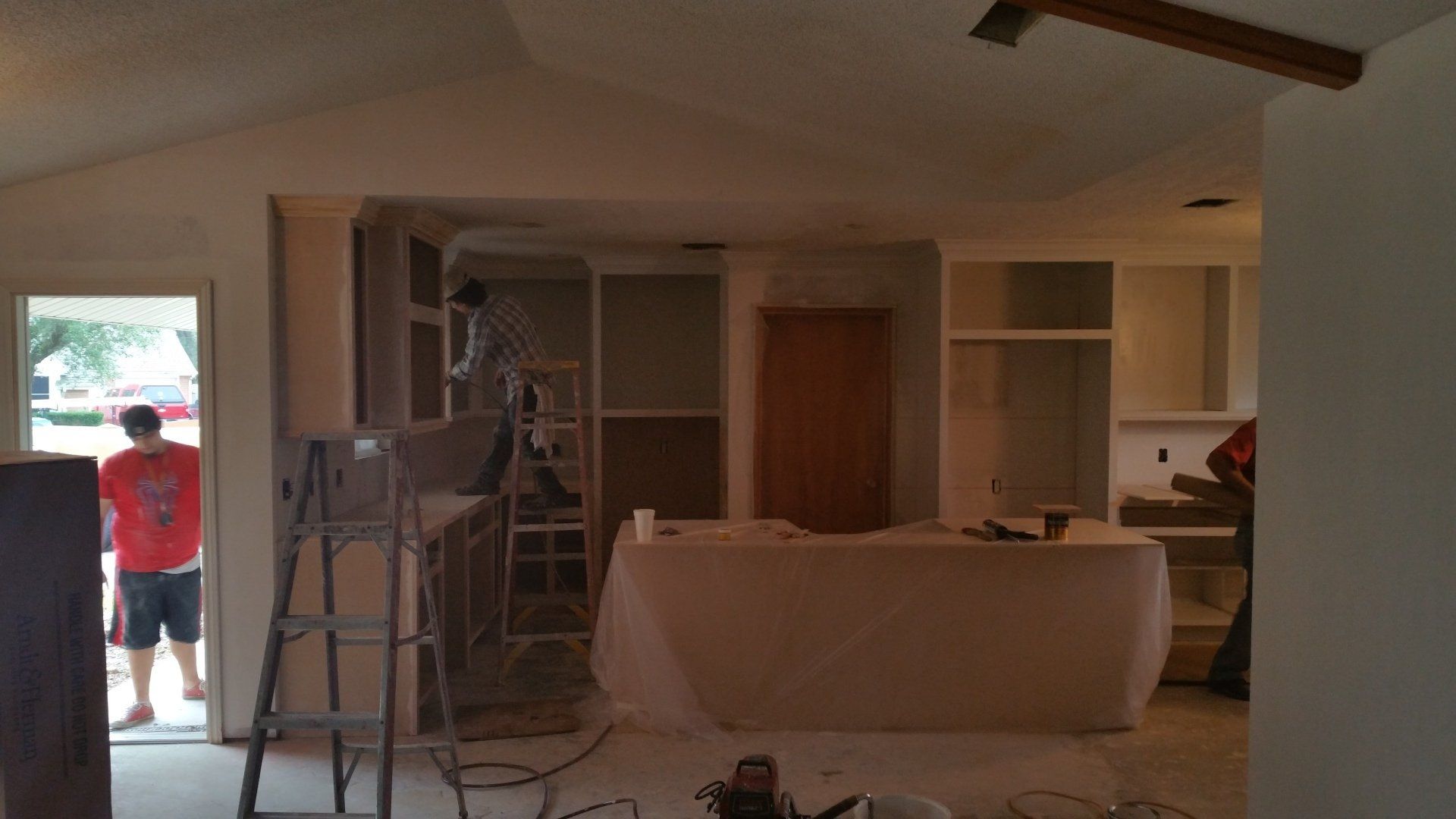 A man is standing on a ladder in a room.