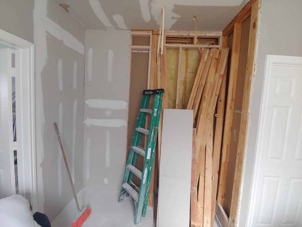 A ladder is leaning against a wall in a room under construction.