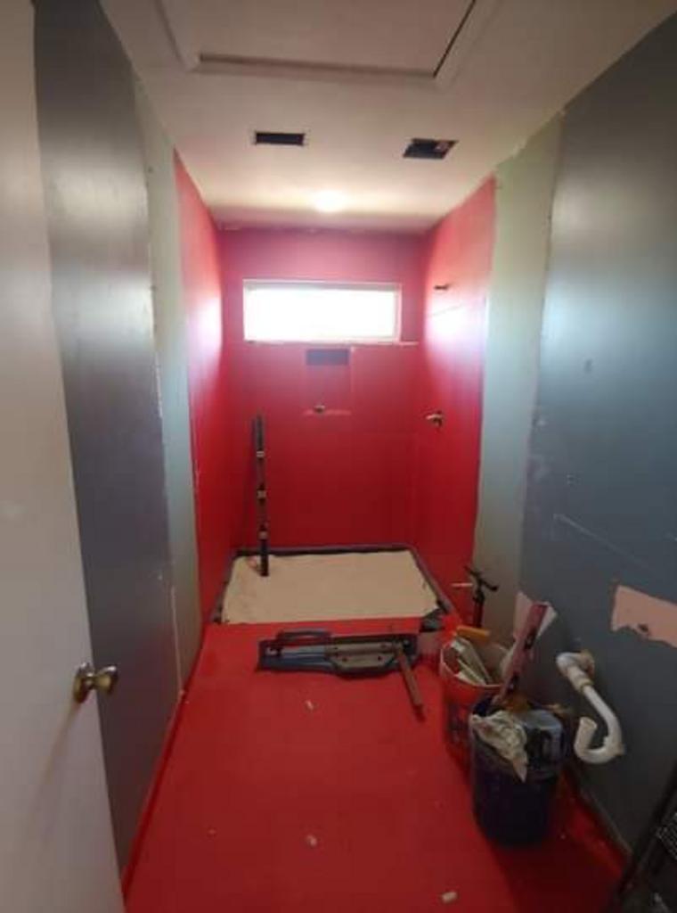 A bathroom with red walls and a red floor is being remodeled.